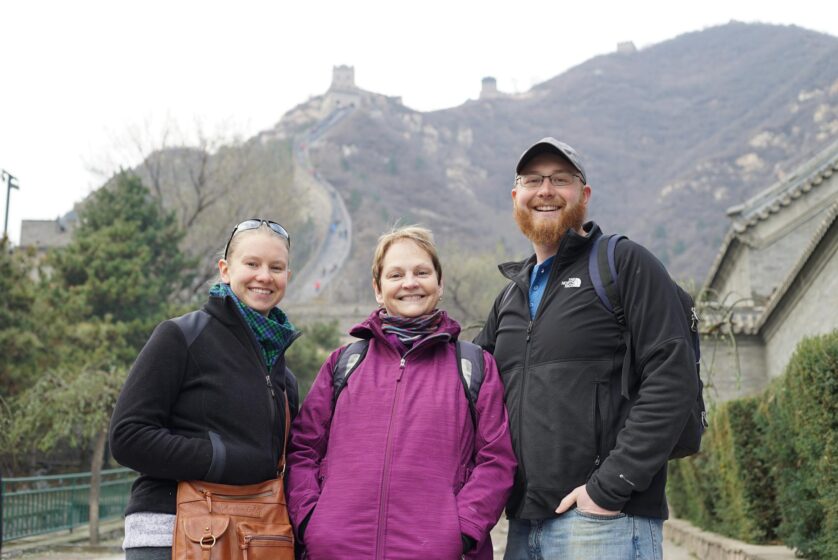 two women and man posing in front of a mountain and smiling